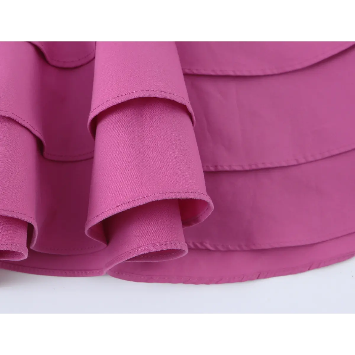 Close-up of the tiered ruffled hem on the magenta halter mini dress
