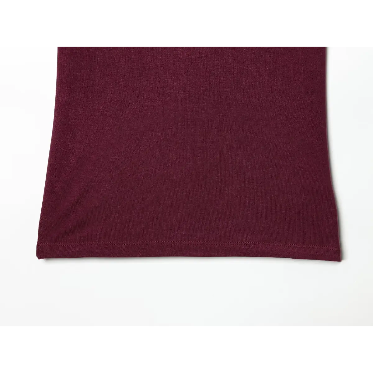 Bottom hem detail of maroon ringer t-shirt, showing the finished edge and fabric texture
