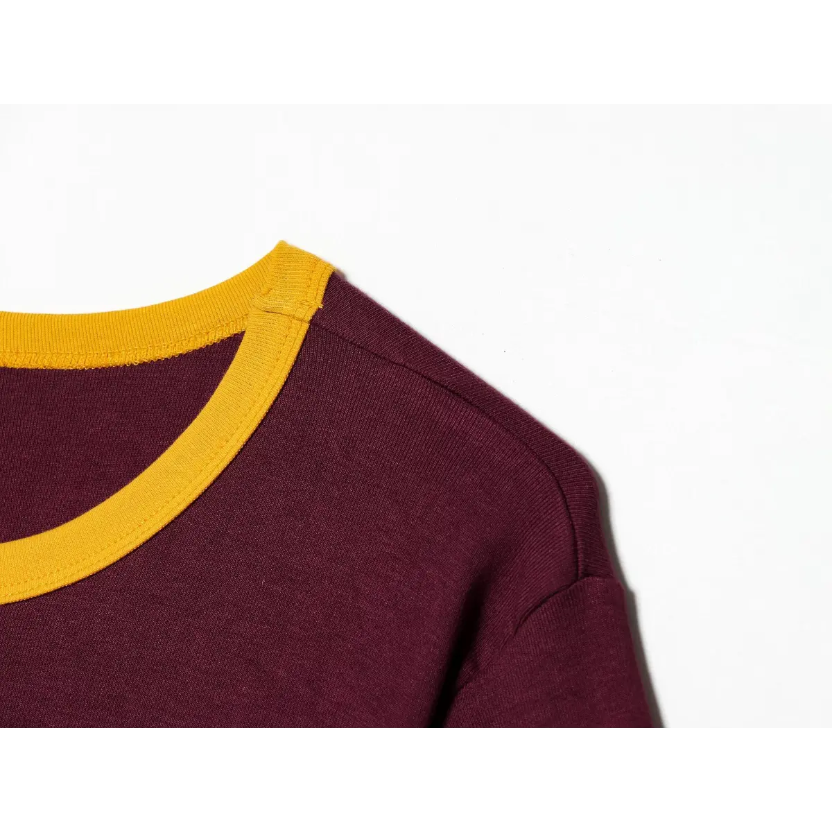 Neckline detail of maroon ringer t-shirt, showing the yellow ribbed crew neck and stitching