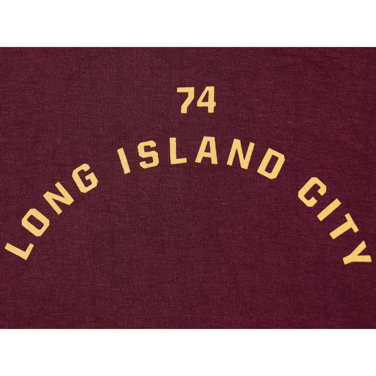 Close-up of the "74 LONG ISLAND CITY" print on the maroon ringer t-shirt