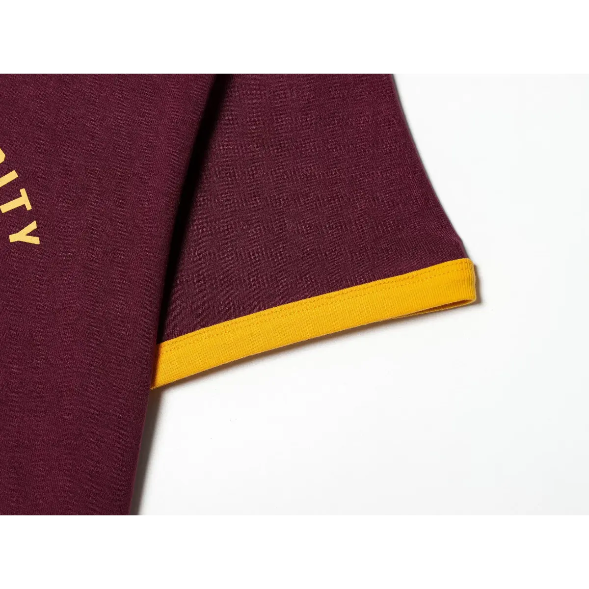 Sleeve cuff detail of maroon ringer t-shirt, showing the yellow ribbed trim and stitching