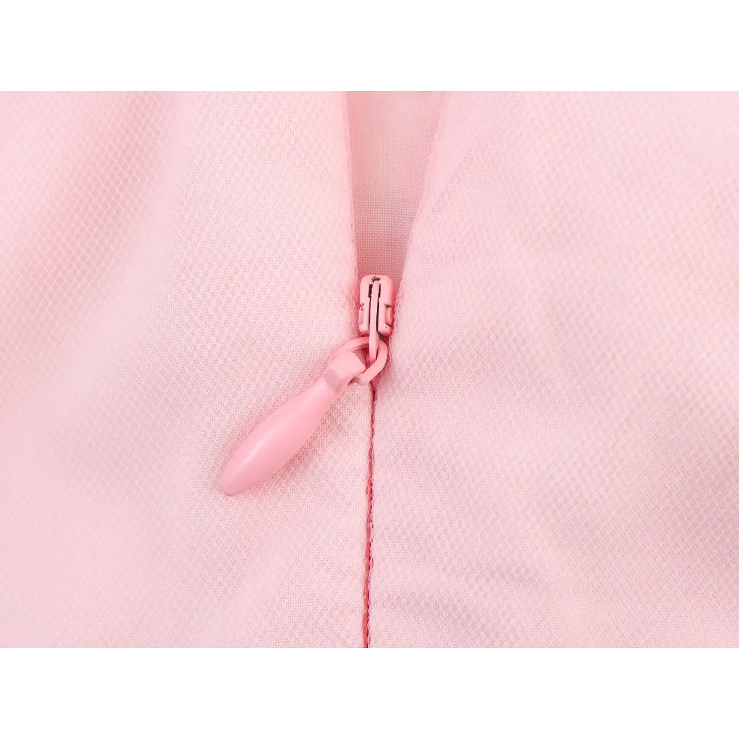 Macro close-up of coated light pink invisible zipper with teardrop fabric pull tab, set against fine mesh lining of halter midi dress