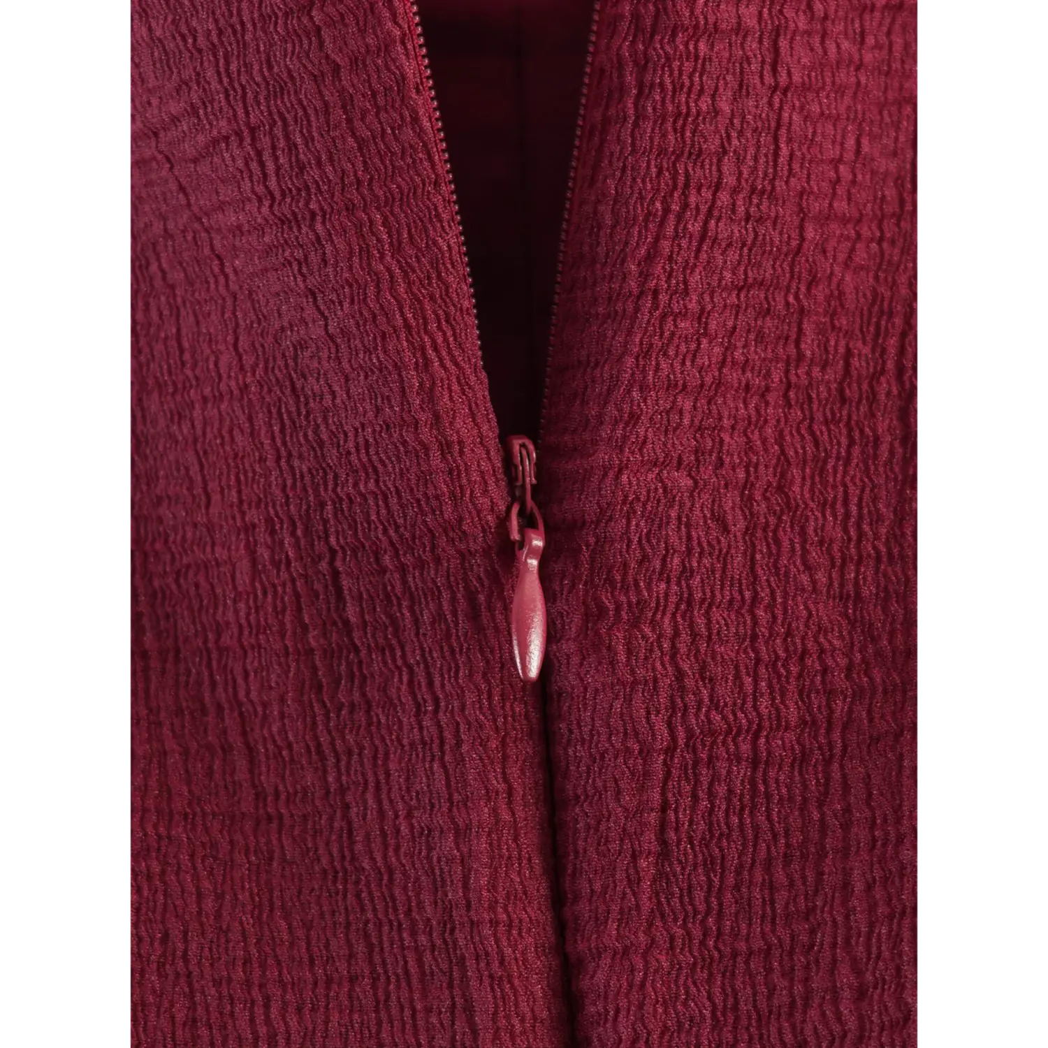 Macro shot coated burgundy invisible zipper, teardrop fabric pull tab blending into wrinkled shell fabric