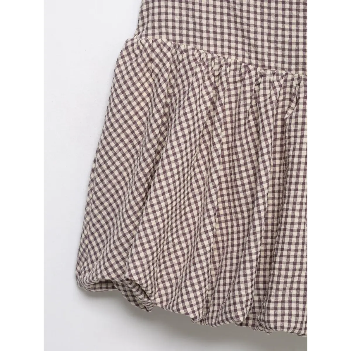 Close-up of the tiered skirt on the mauve gingham dress, showing the gathered bubble hem and fabric texture