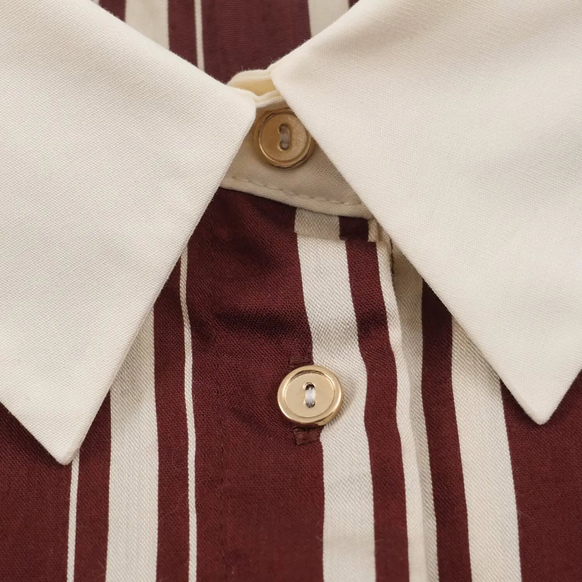 Macro shot of gold round buttons and pointed cream collar on striped shirt maxi dress