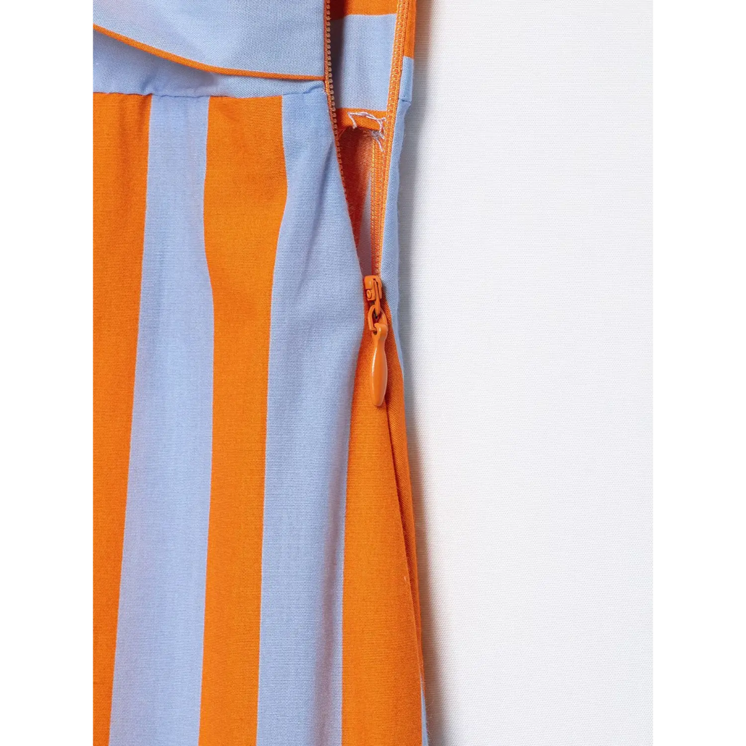 Close-up side invisible zipper detail on orange blue striped spaghetti strap maxi dress