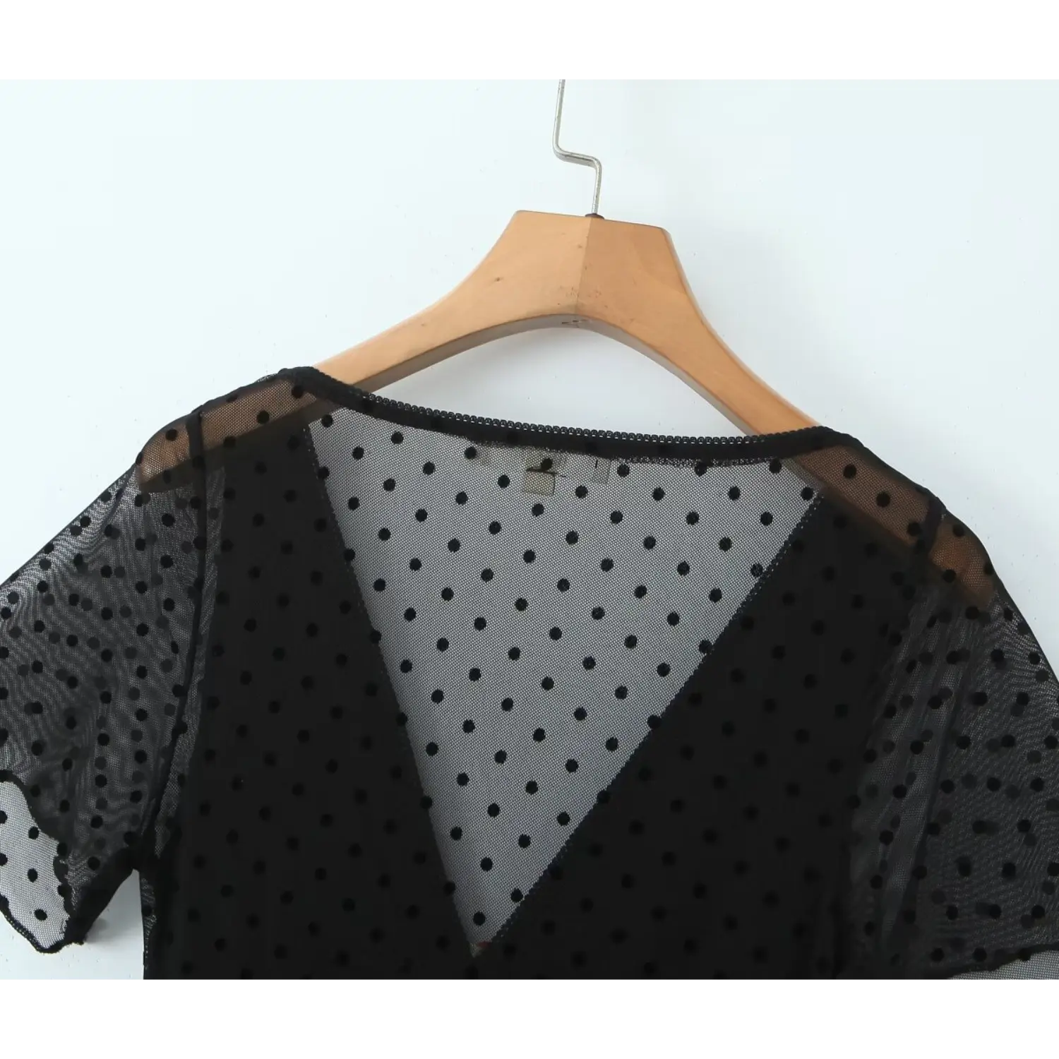 Close‑up back neckline of black polka dot sheer mesh dress, scalloped trim detail