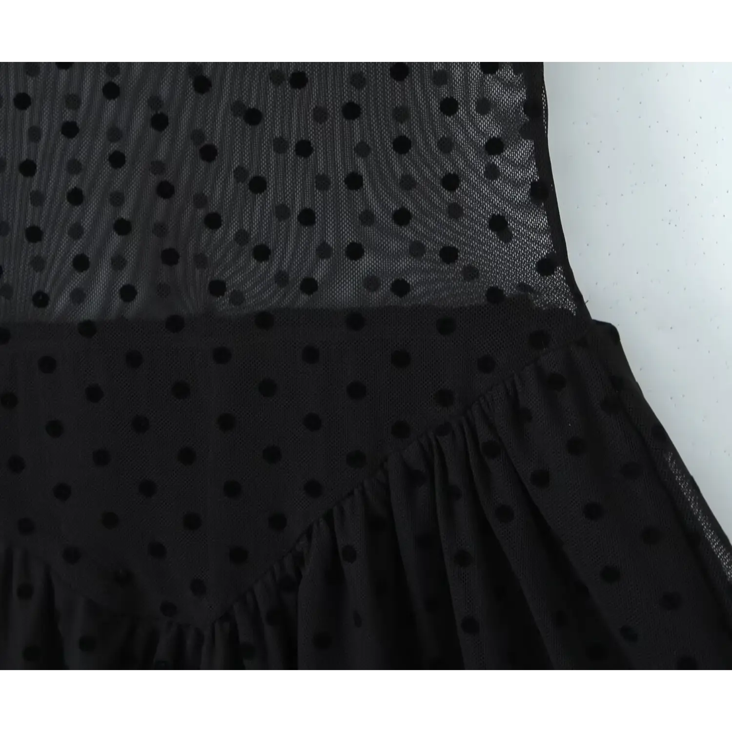 Close‑up waist seam and gathered skirt of black flocked polka dot mesh mini dress, sheer mesh fabric texture