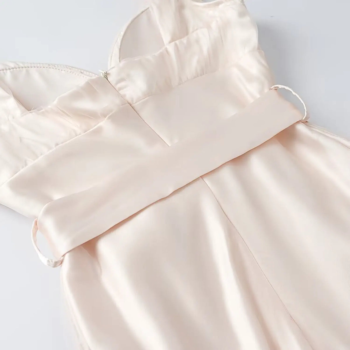 Close-up of back waist zipper and satin waistband on cream women midi dress