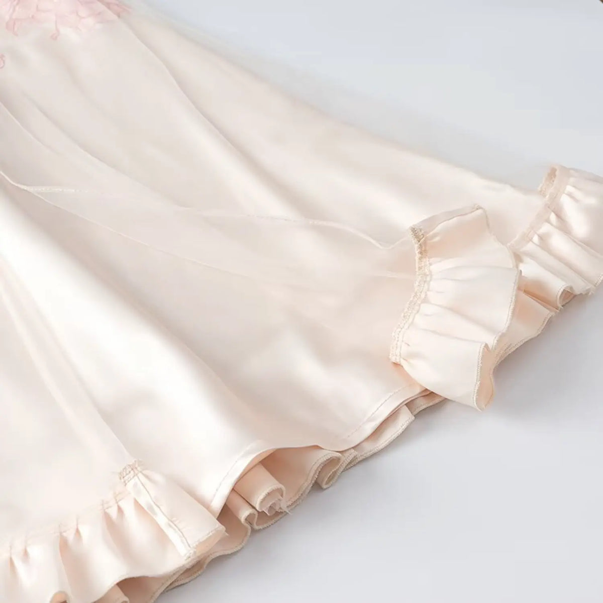 Close-up of ruffled hem on cream satin midi dress, smooth shiny fabric