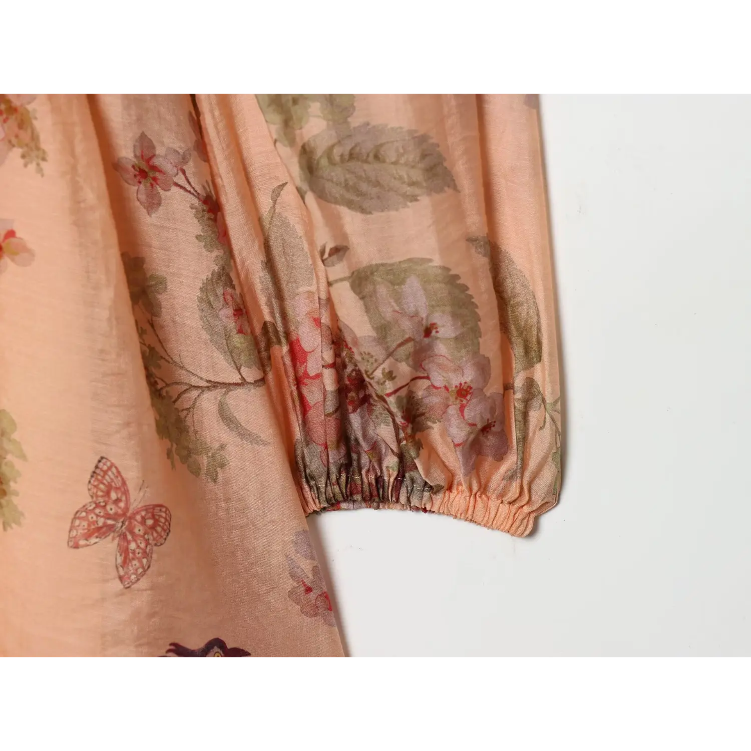 Close‑up of elasticated balloon sleeve cuff, ruched finishing, peach botanical bird print fabric