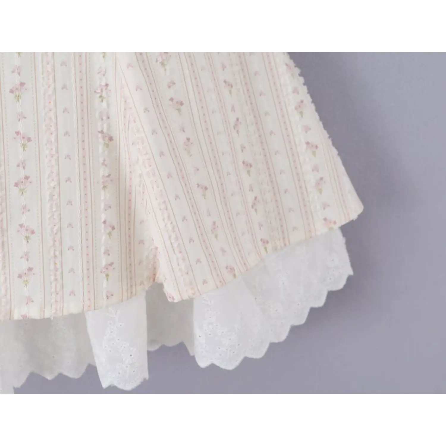 Skirt hem close-up double layer design, outer floral woven flared frill, inner full cream scalloped eyelet lace slip trim, soft flowy silhouette