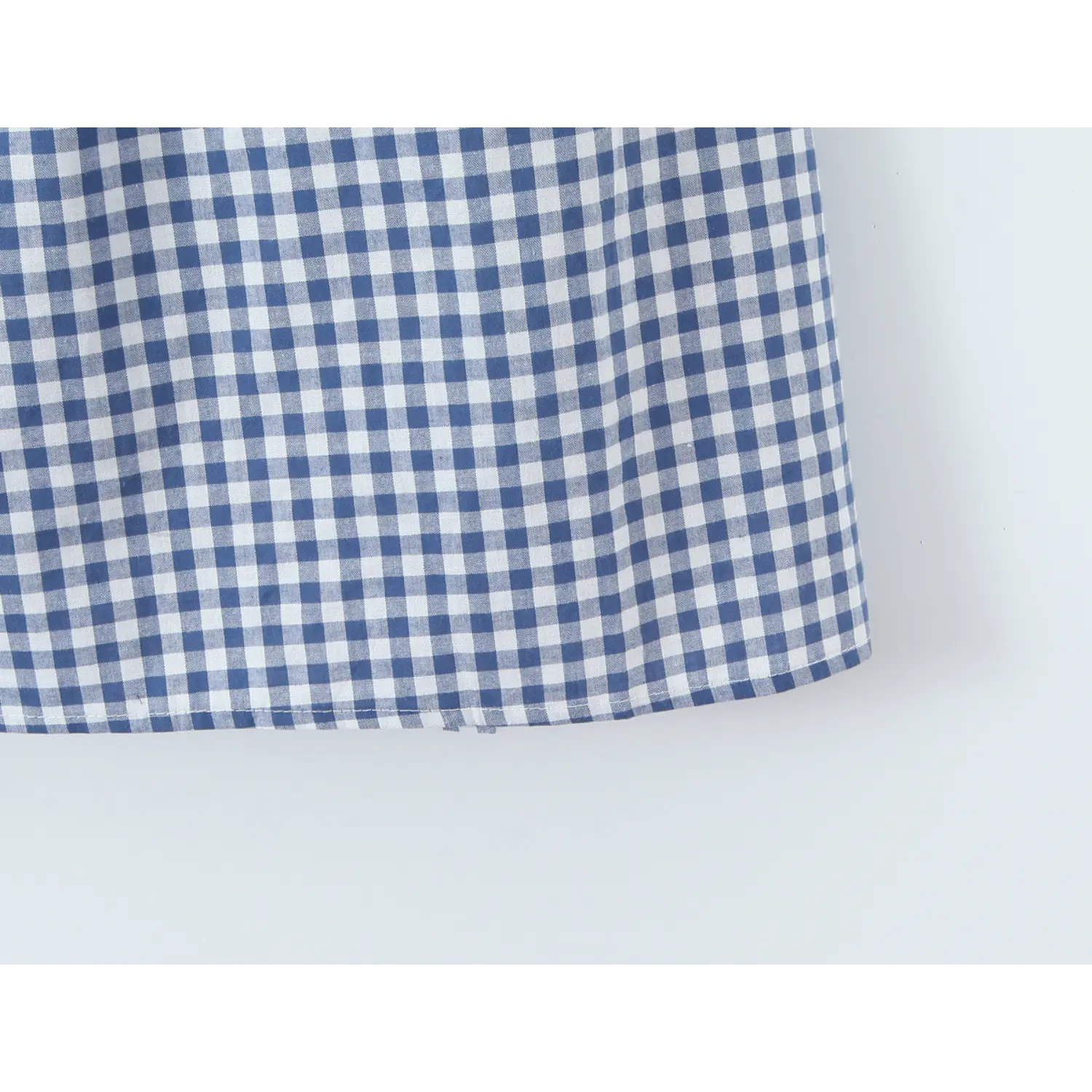 Mini A-line skirt hem binding edge flat overview shot, double thread neat hem loose flared short silhouette soft drape gingham fabric display
