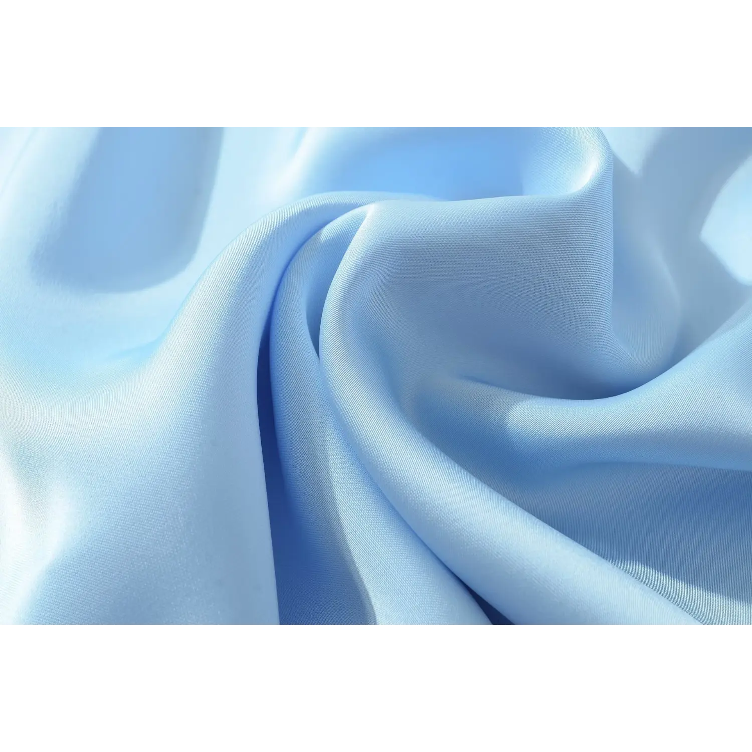 Macro close-up of folded light blue satin fabric, showcasing smooth reflective silky weave texture of women slip dress material