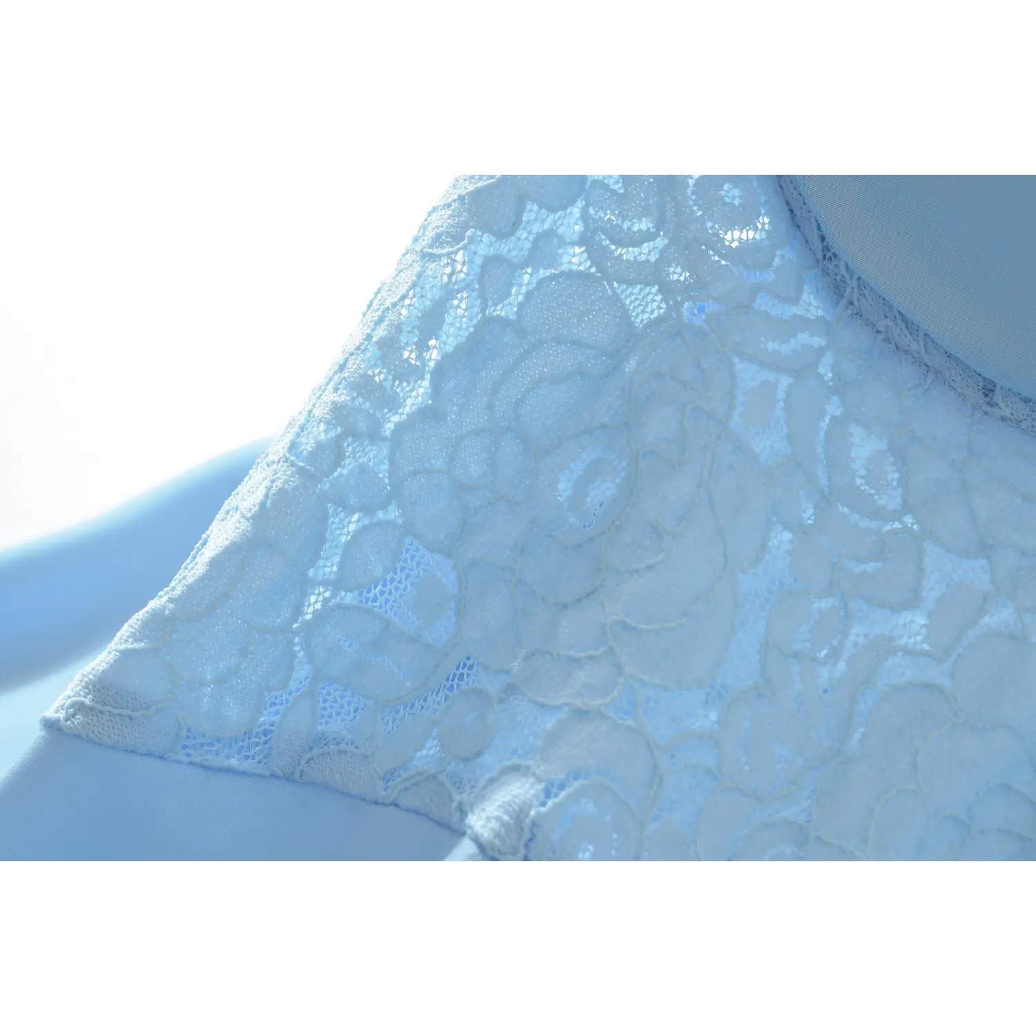 Close macro shot of floral rose lace panel on light blue slip dress bust, hollow semi-sheer texture matched with glossy satin