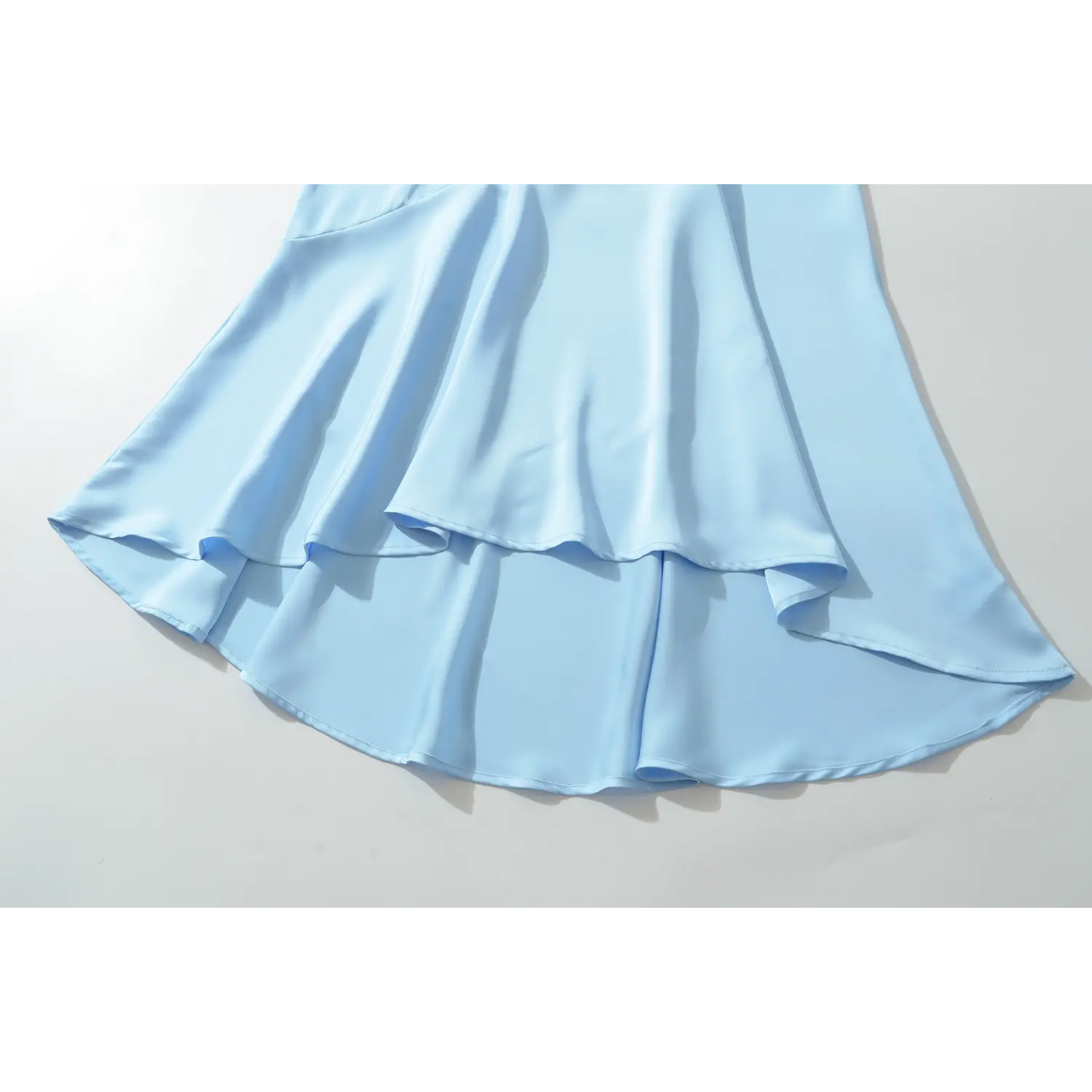 Flat lay partial view of layered flared mermaid skirt, lightweight light blue satin with soft natural draping for evening casual outfit