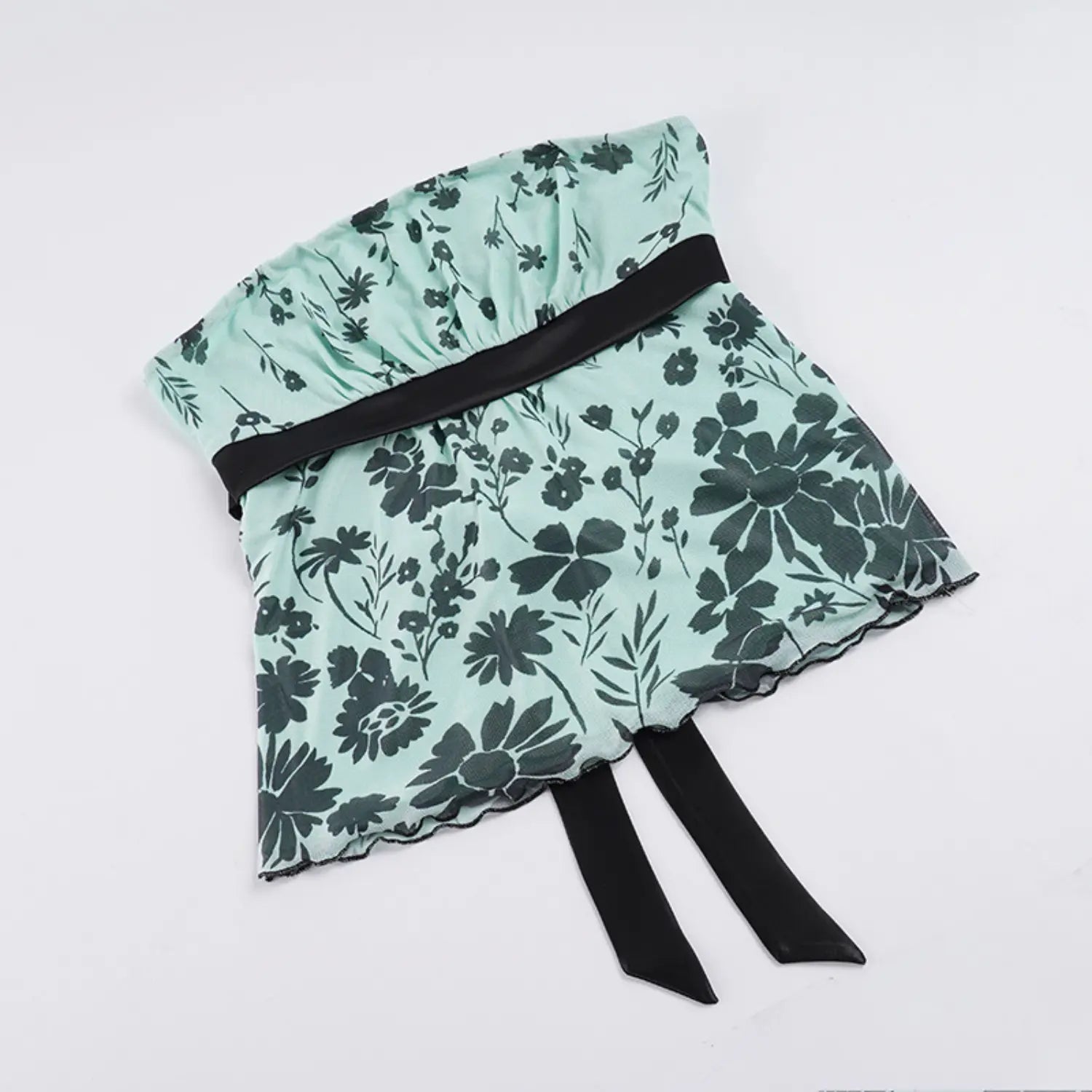 Full flat lay studio shot of strapless mesh tube top on plain white background, elastic gathered bust, black satin waist ribbon with long hanging ties, scalloped wavy mesh hem, dark scattered floral print pattern