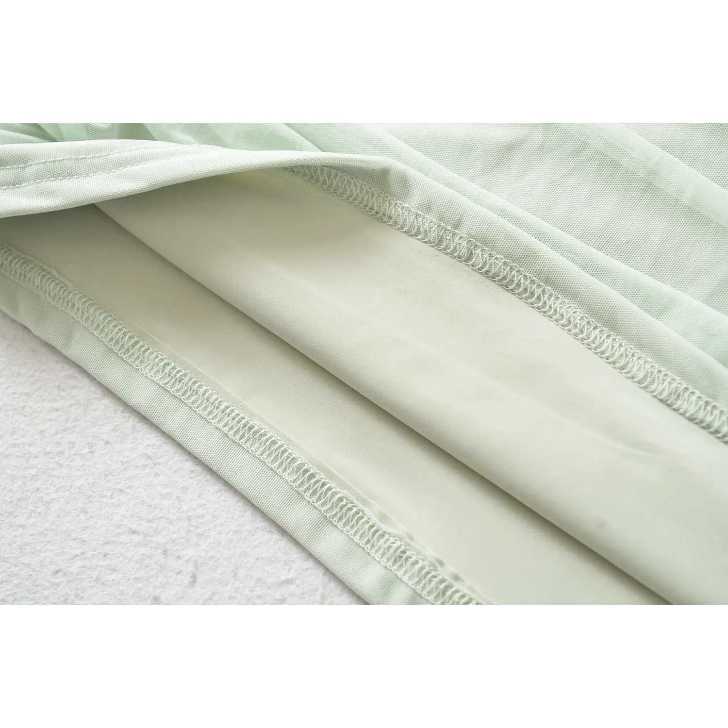 Close-up of mint green halter dress inner lining and neat stitching hem