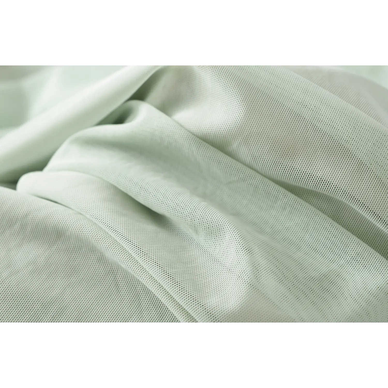 Macro shot of mint green sheer mesh fabric, soft stretch texture for halter bodycon dress