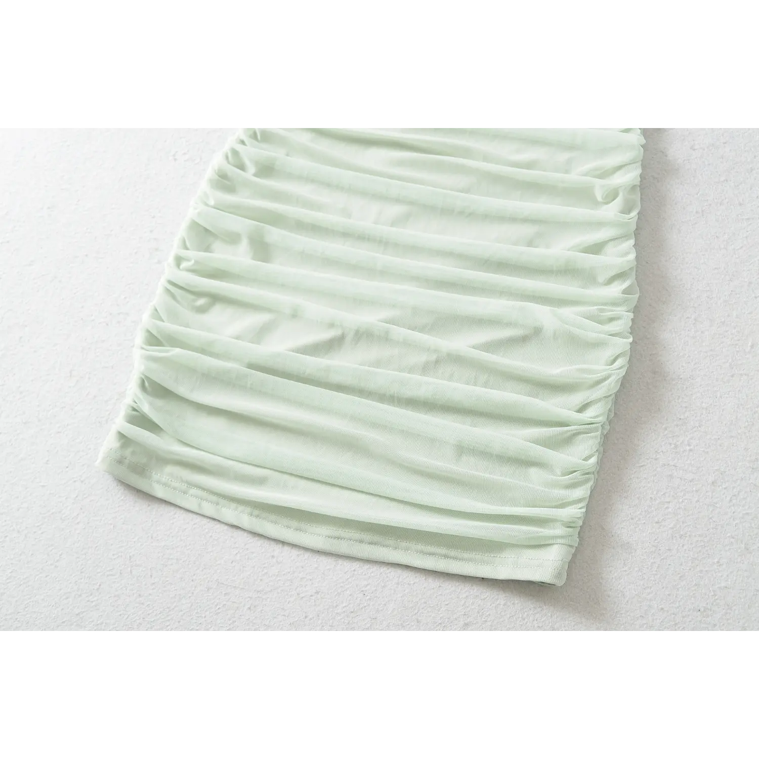 Close-up of mint green halter bodycon dress skirt, horizontal mesh ruching texture
