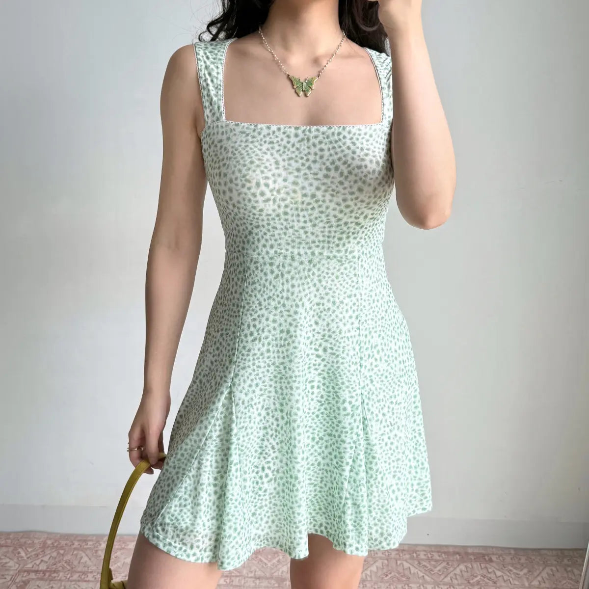 Angled view of a mint green leopard print flare mini dress, highlighting the fitted bodice, square neck, and flared skirt.