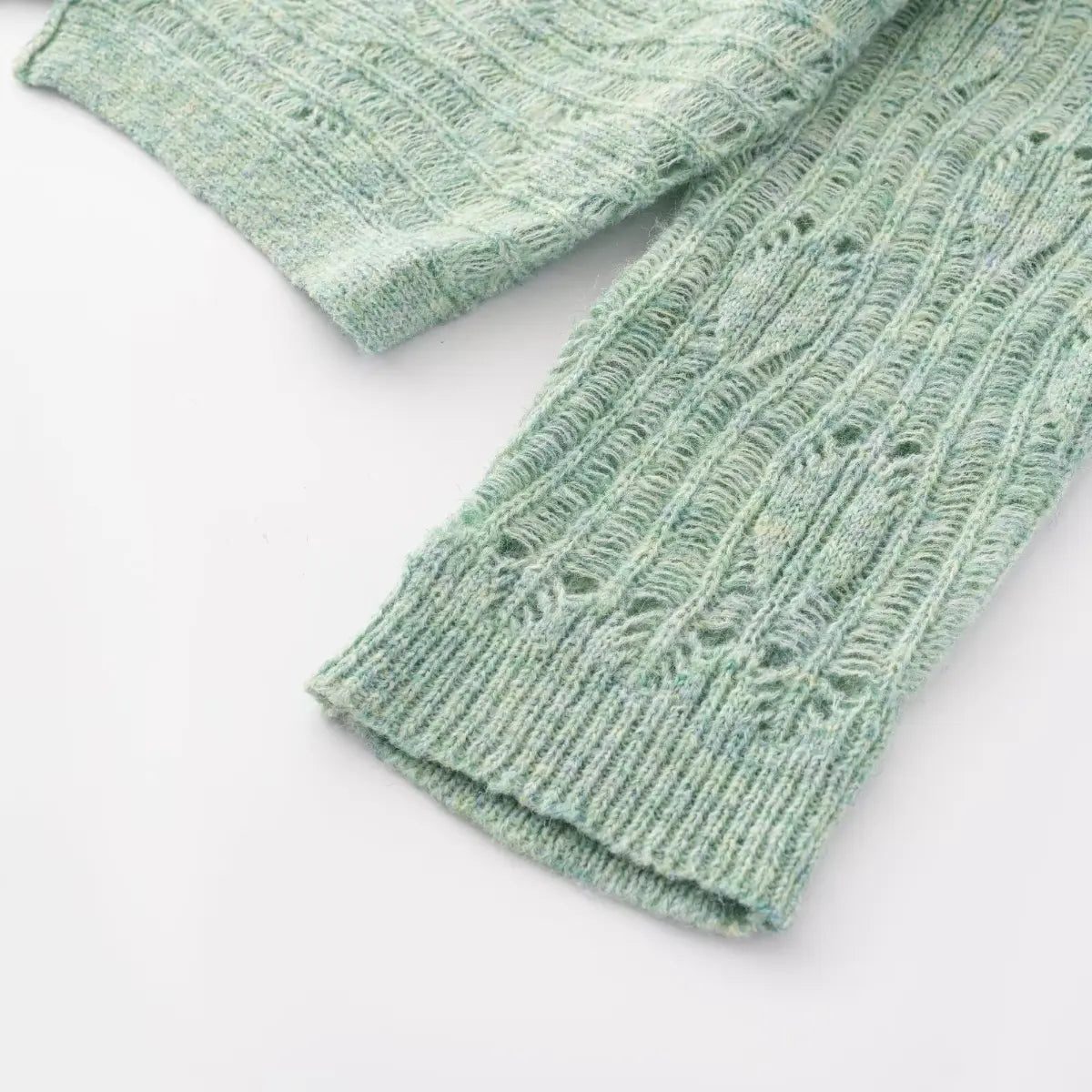 Close-up view of the ribbed sleeve cuffs on a mint green openwork knit cardigan, showing the pattern transition.