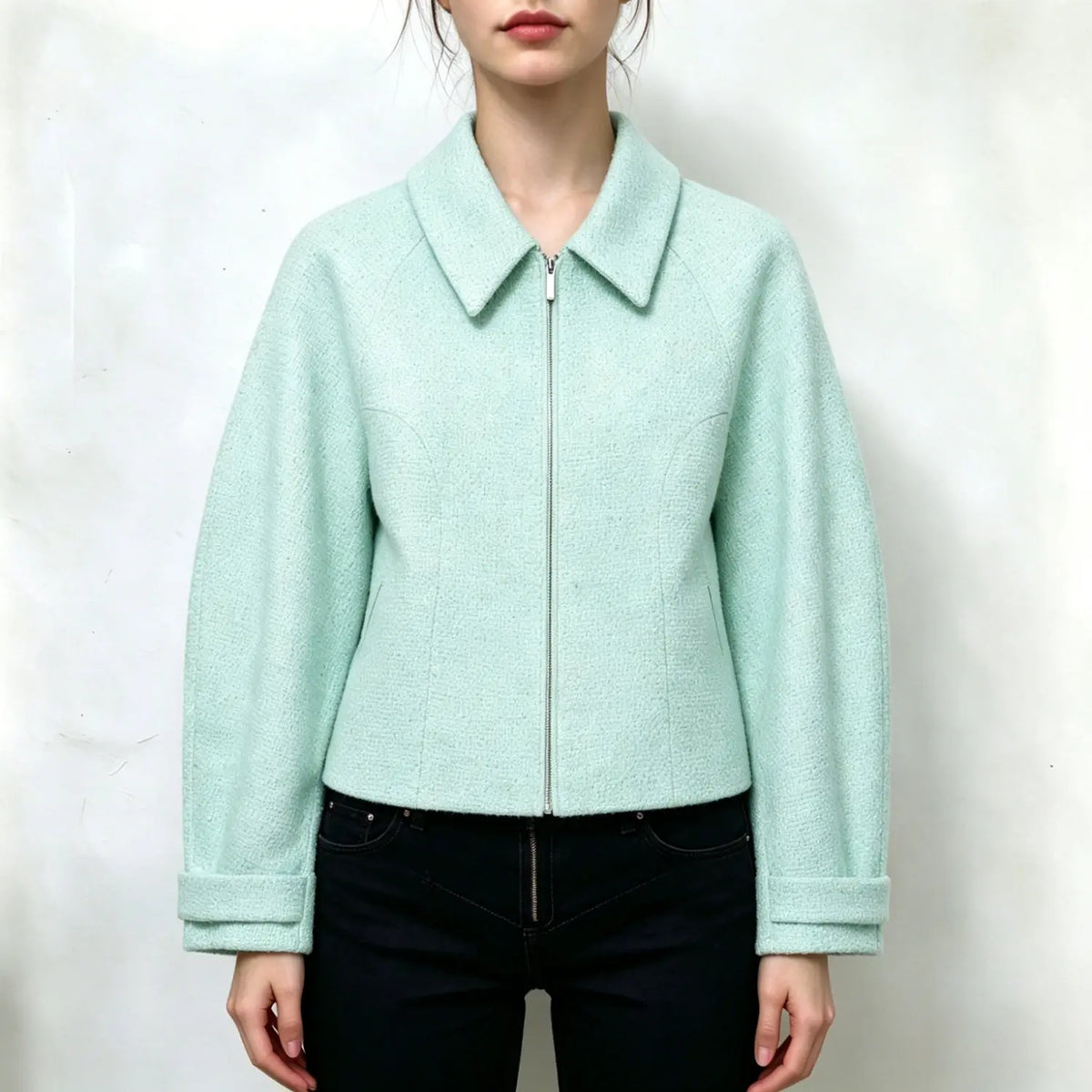 Model wearing mint green tweed cropped jacket, point collar, full front zipper, raglan long sleeves with folded cuffs, side pockets, relaxed fit, paired with black jeans, plain white background