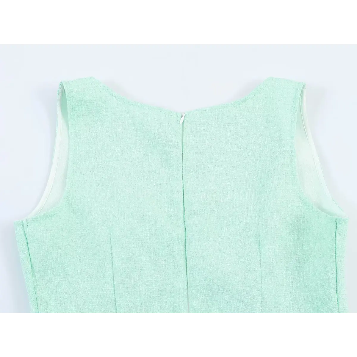 Back view close-up of a mint green tweed sleeveless dress, showing the center-back zipper closure and structured bodice seams.
