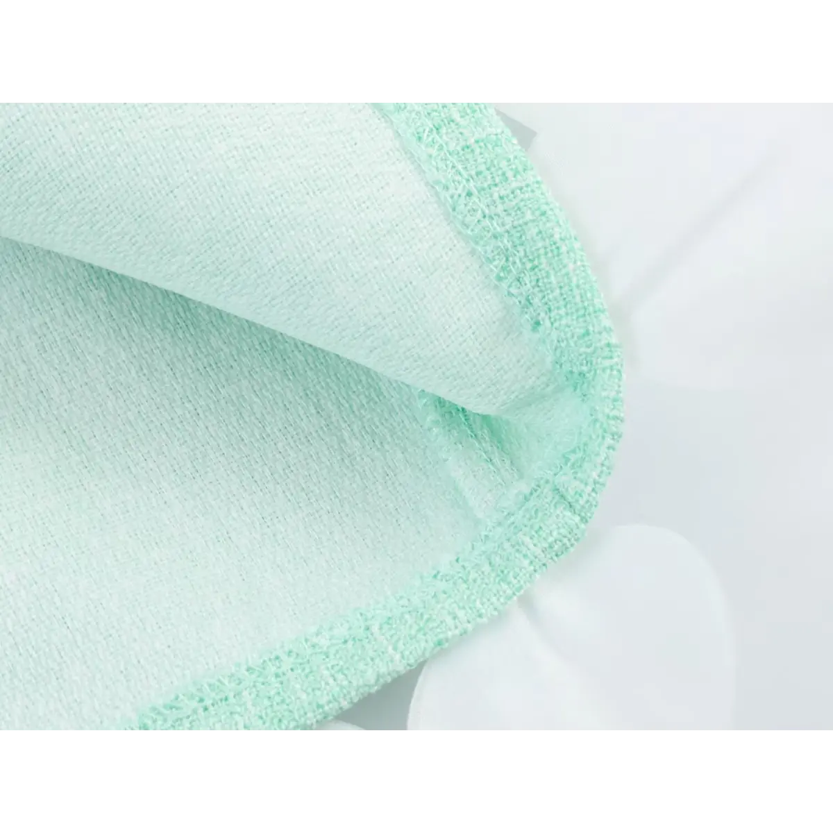 Close-up of the fabric texture and inner lining of a mint green tweed dress, showing the finished hem.
