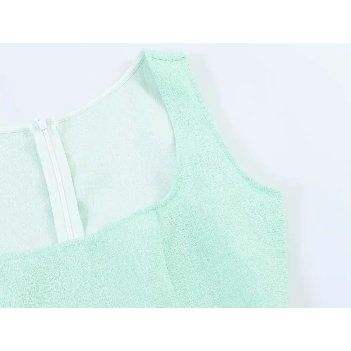 Close-up of the square neckline, shoulder seam, and back zipper on a mint green tweed dress.