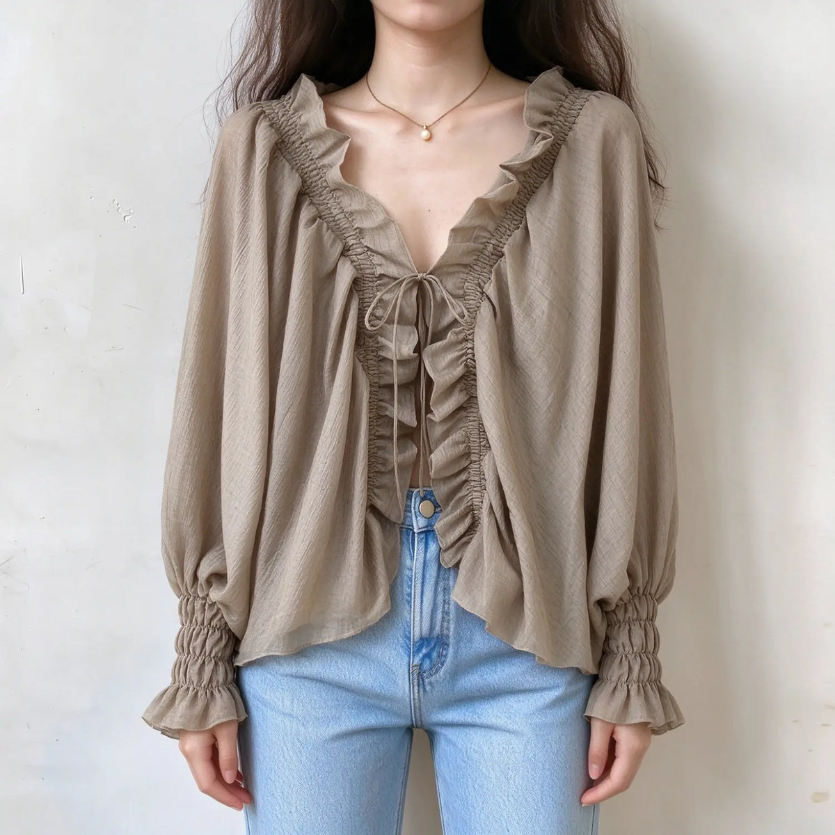Model wearing mocha ruffle tie front smocked blouse, front view