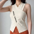 Female model wearing cream wrap cross halter top with vertical black buttons, studio outfit shot