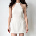 Female model wearing white halter sleeveless side lace-up fit flare mini dress, studio shot