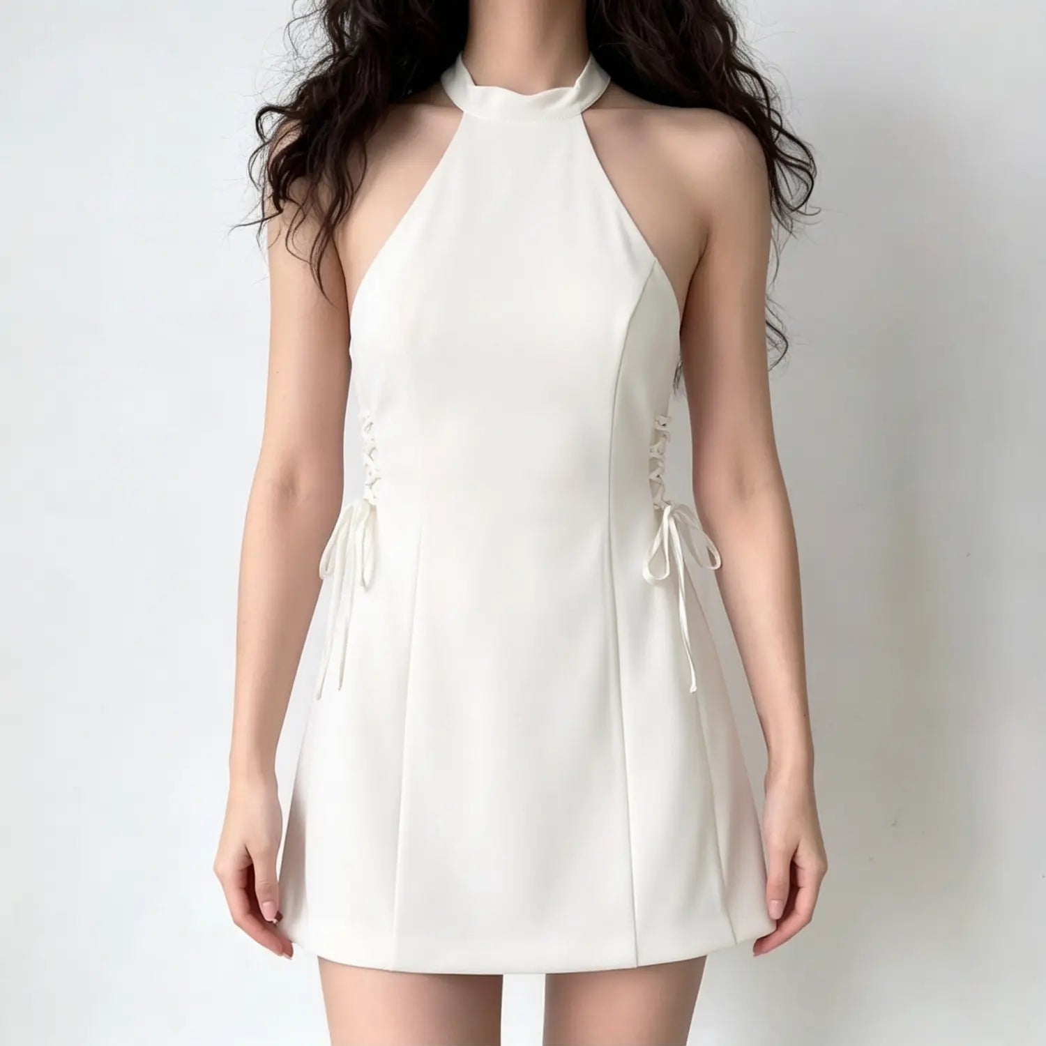 Female model wearing white halter sleeveless side lace-up fit flare mini dress, studio shot
