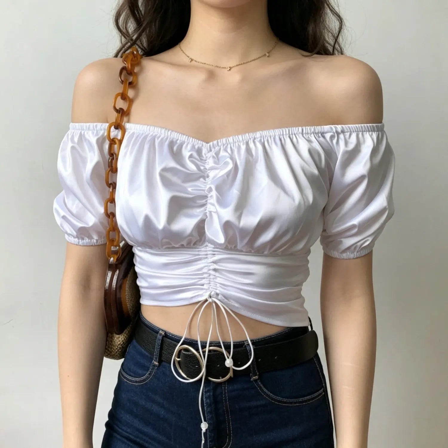 Front full shot lady in white off shoulder satin ruched drawstring crop top matched with jeans