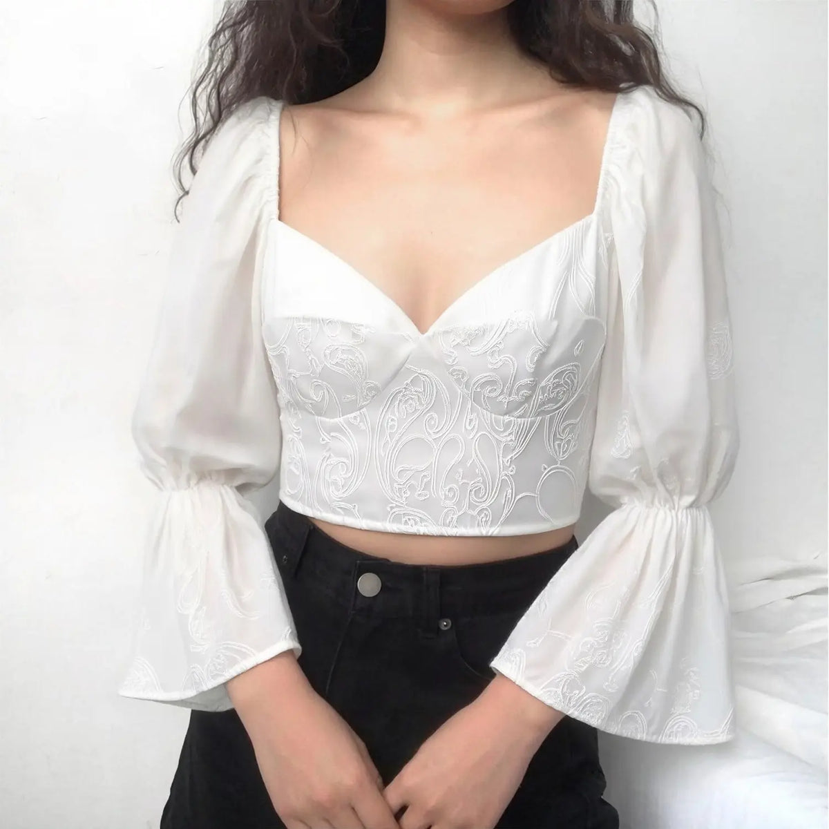 Female model wearing white embroidered bustier crop top with long bell puff sleeves