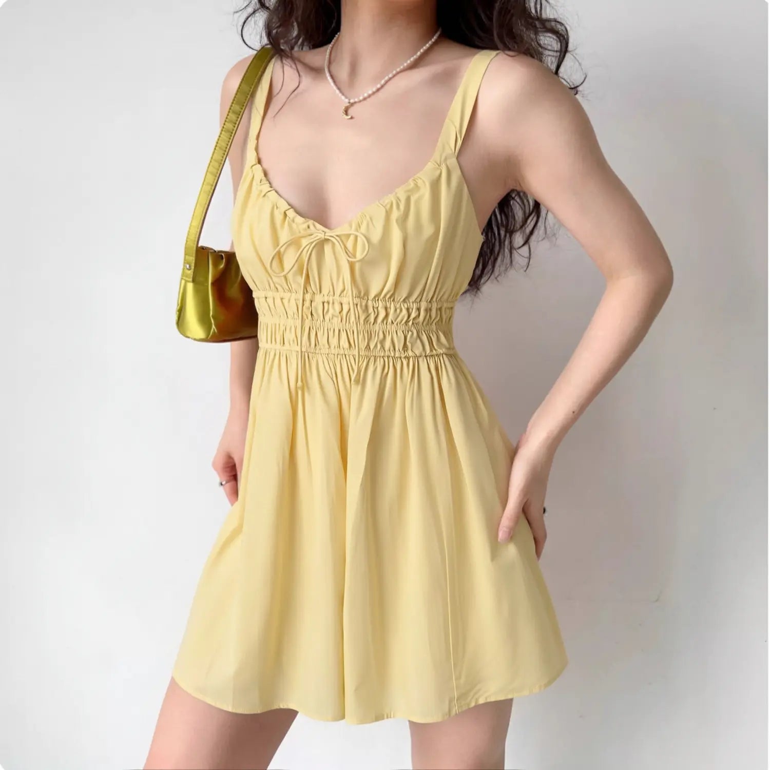 Female model posing in yellow tie‑front smocked waist cami mini sundress, casual summer look