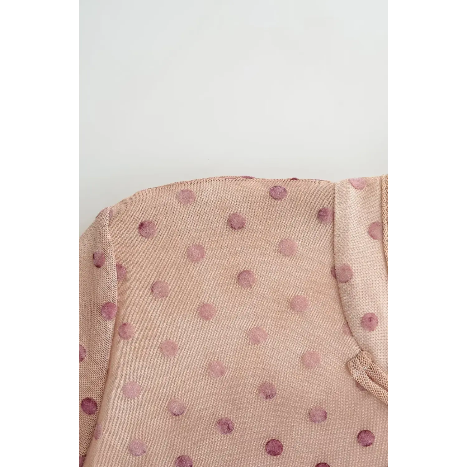 Extreme close-up of sheer blush mesh fabric with flocked velvet pink polka dots, showing lightweight stretch texture of cheongsam outer layer