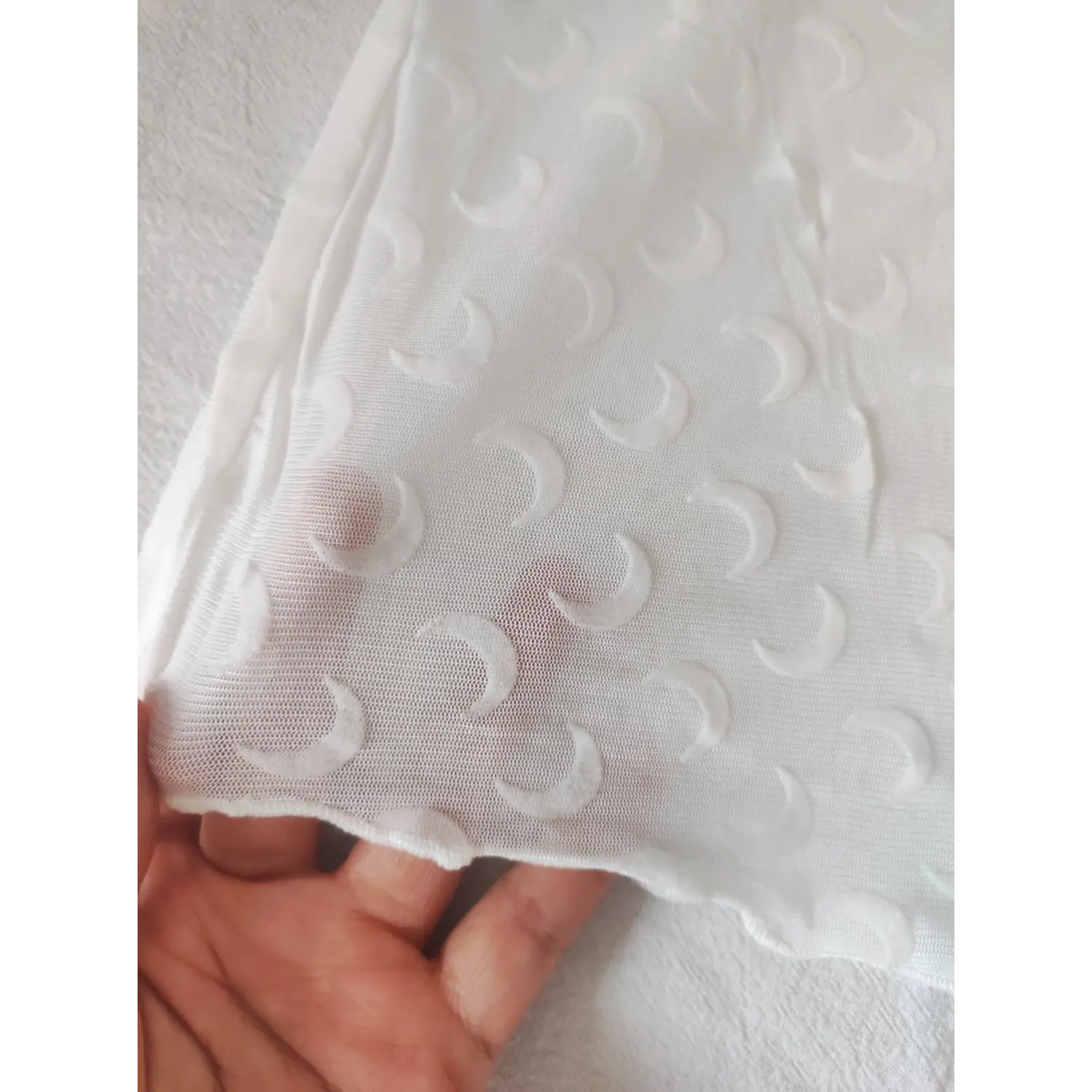Close up texture of white mesh fabric with embossed crescent moon print