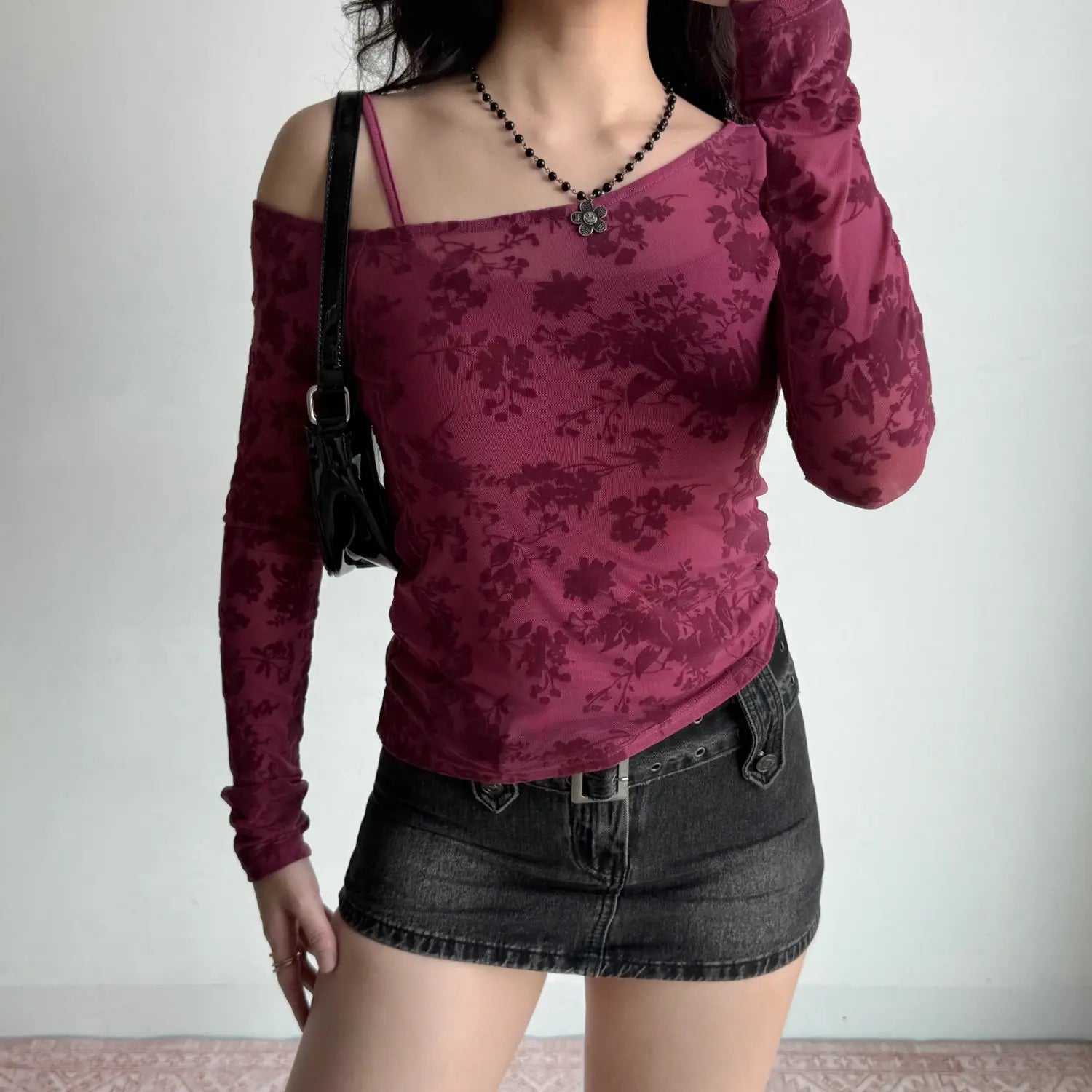 Lifestyle styling shot mulberry pink floral mesh off‑shoulder long sleeve top with black shoulder bag