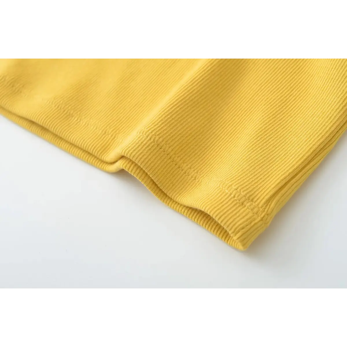  Close-up of the double-stitched hem on the mustard yellow ribbed camisole