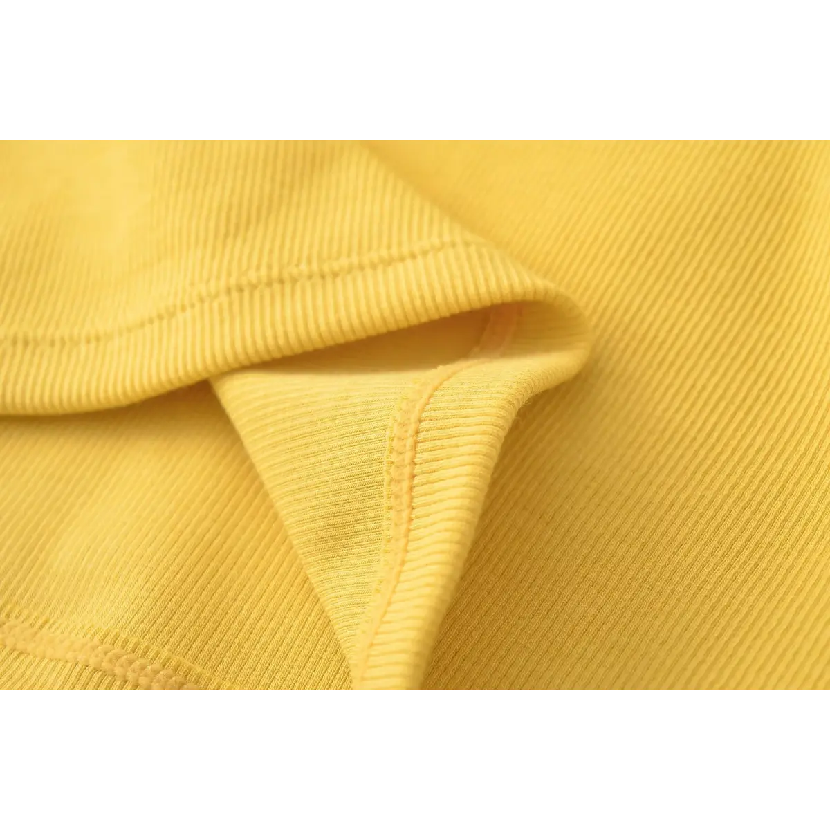 Close-up of the ribbed fabric texture and hem stitching on the mustard yellow camisole