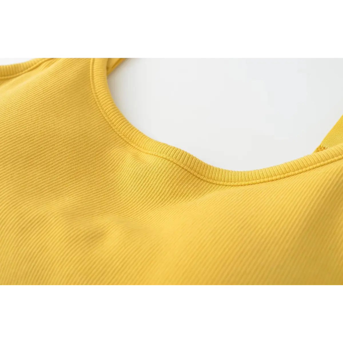 Close-up of the ribbed scoop neckline stitching on the mustard yellow camisole