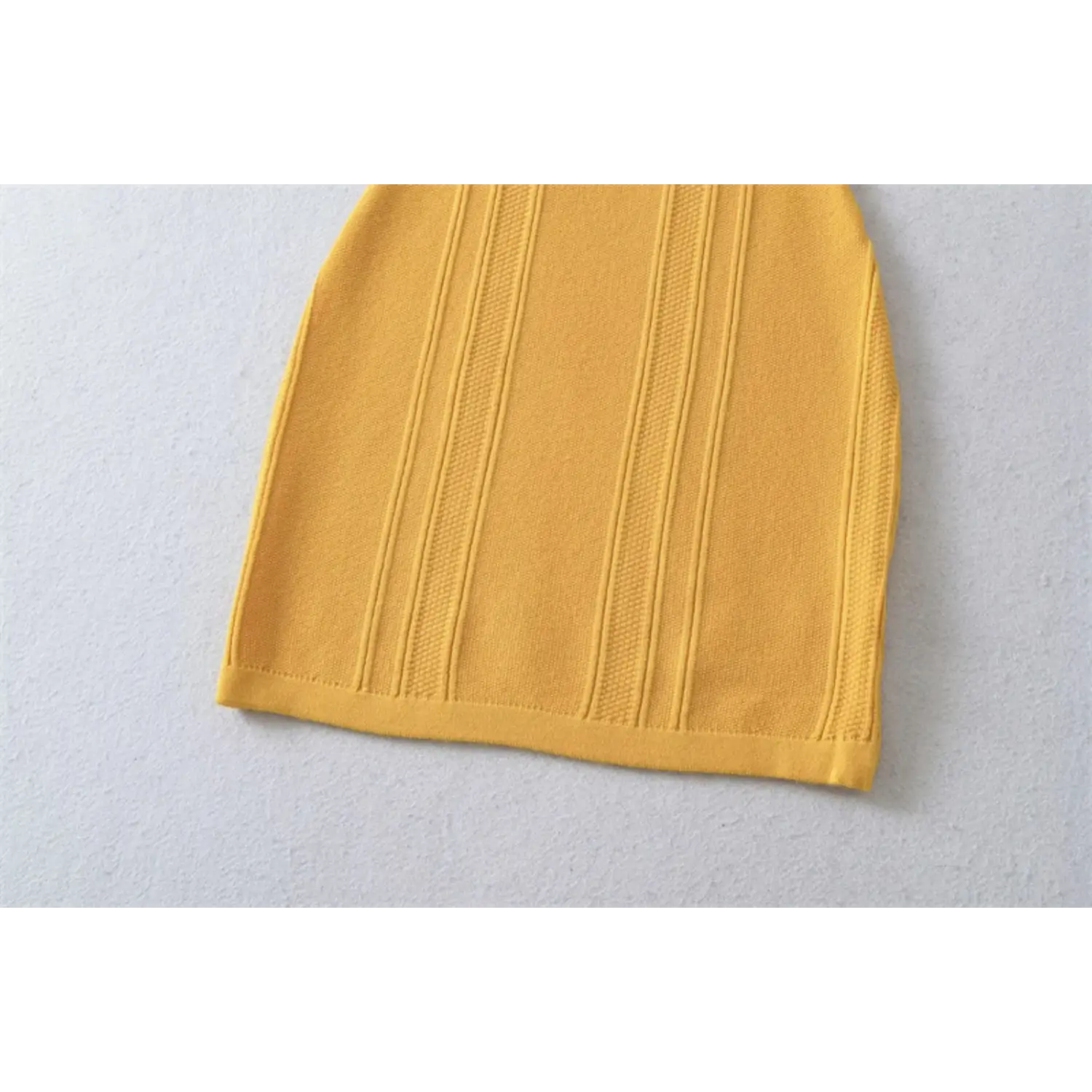 Mustard yellow vertical ribbed knit mini dress hem flat close-up, 3D stripe stretch knit neat edge stitching white background shot
