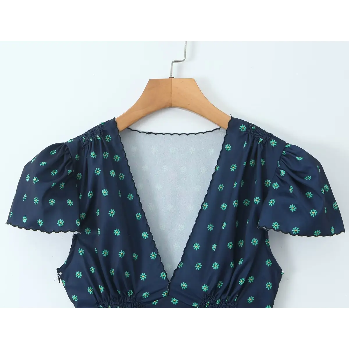 Close-up of the deep V-neck, showing the scalloped trim and puffed short sleeves