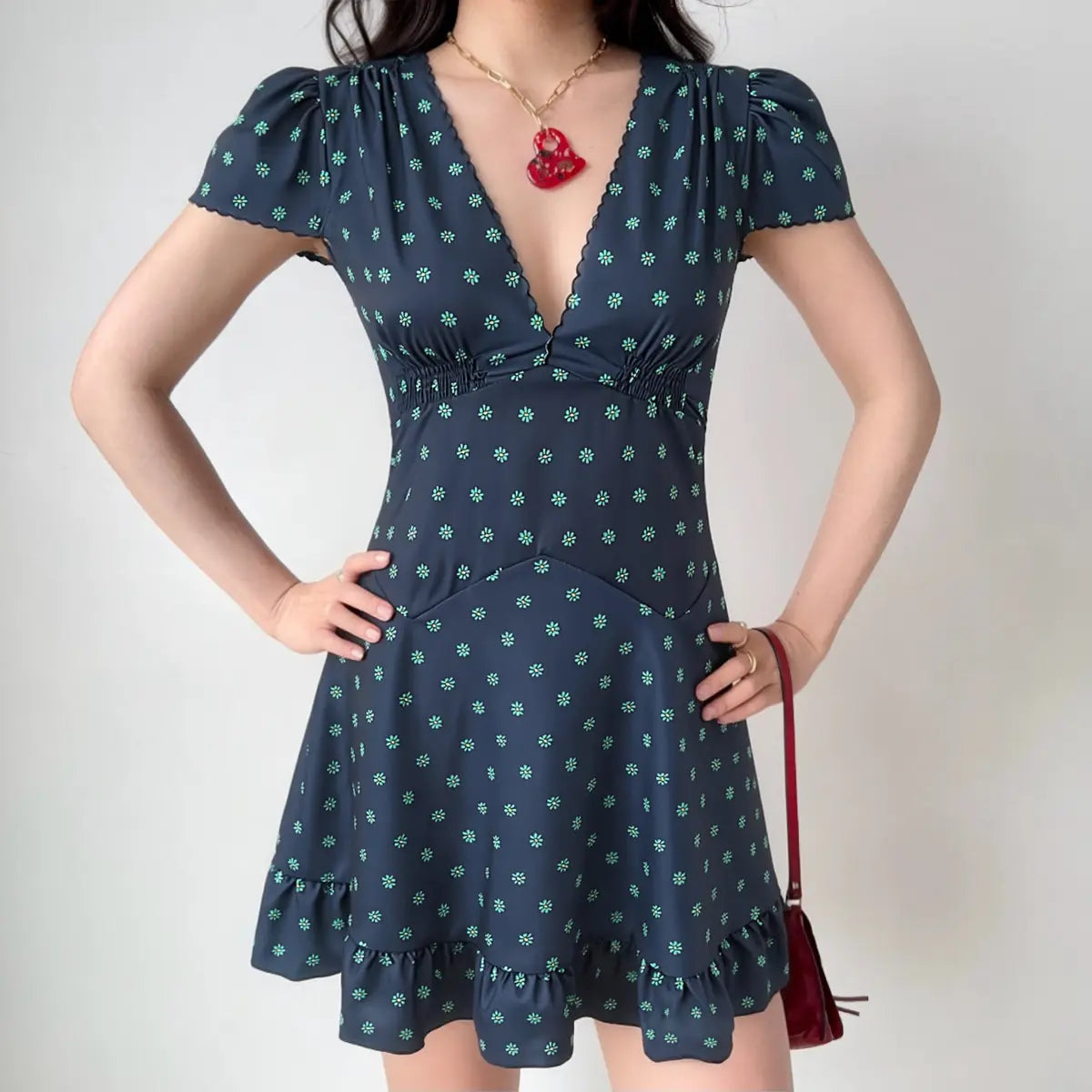 On-model view of the dress, showing the deep V-neck, smocked waist, and tiered skirt silhouette.