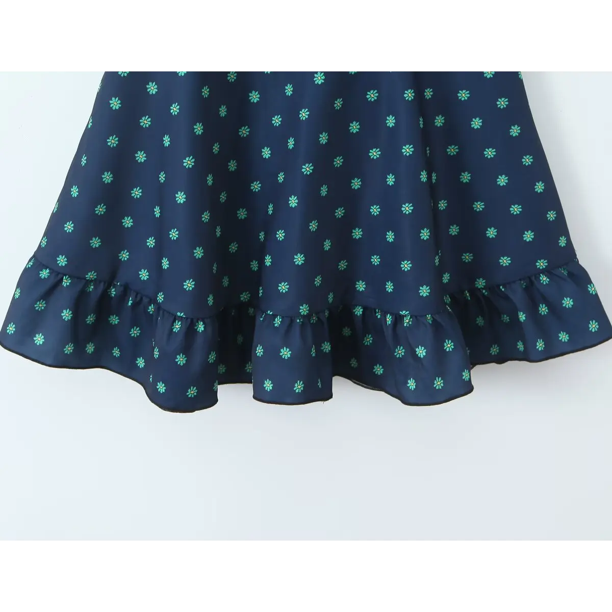 Close-up of the ruffled skirt hem, showing the green floral print and finished edge.