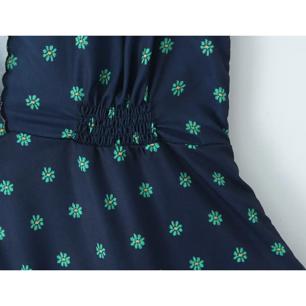 Close-up of the elasticated smocked waist, showing the floral print fabric and gathered construction.