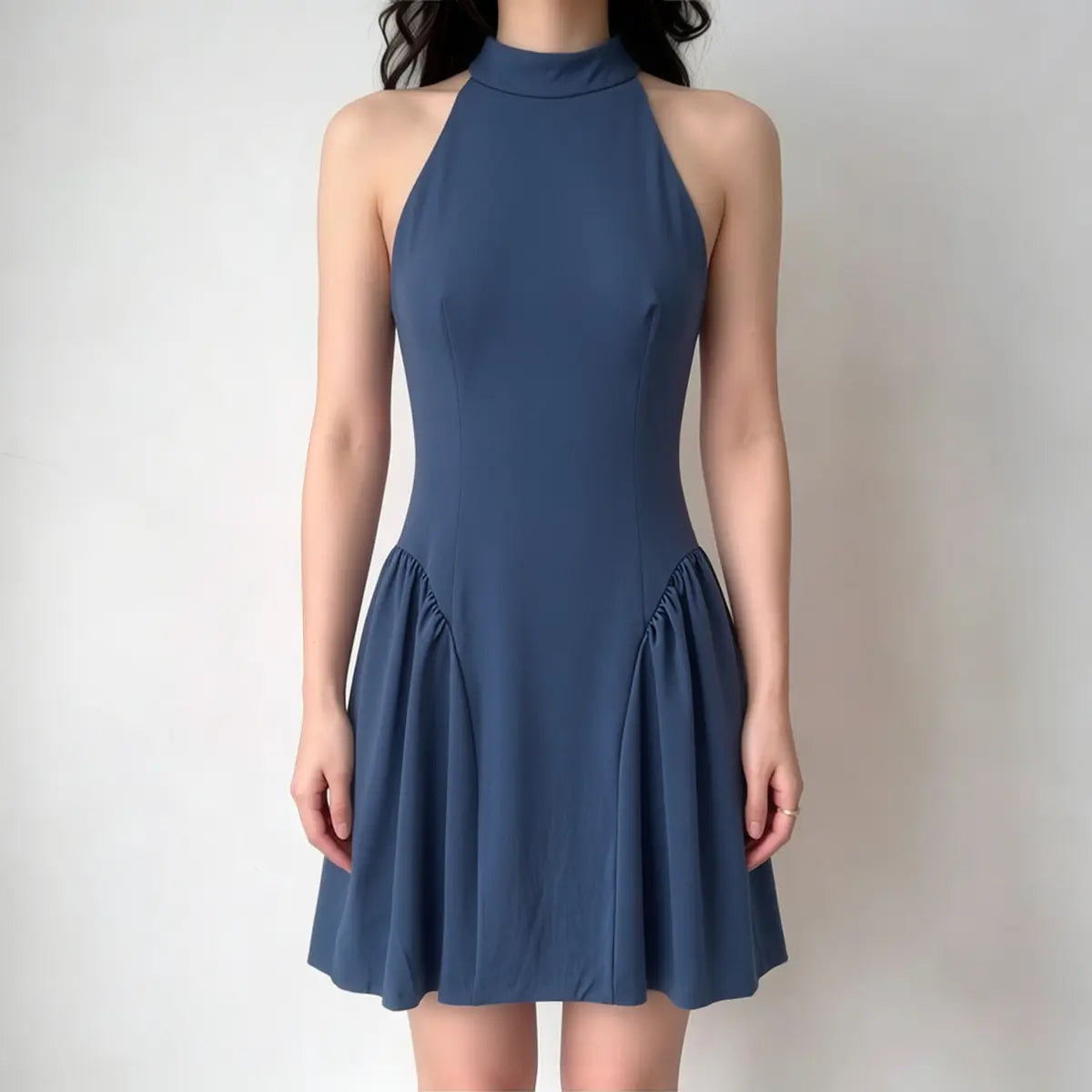 Model wearing a navy blue halter-neck mini dress with a high neckline, fitted bodice, and gathered flared skirt, front view.