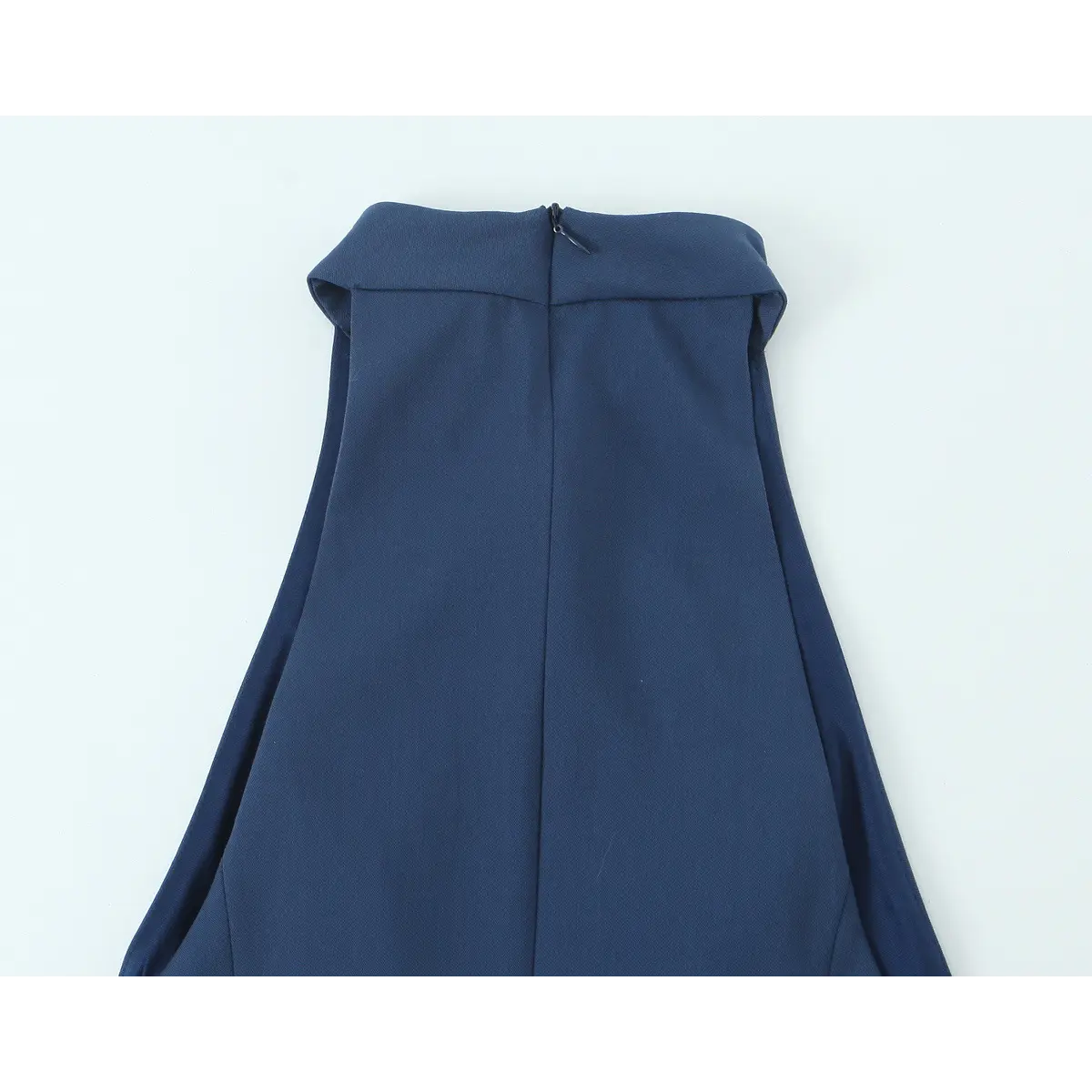 Close-up back view of the high halter neckline and zipper on a navy blue mini dress.